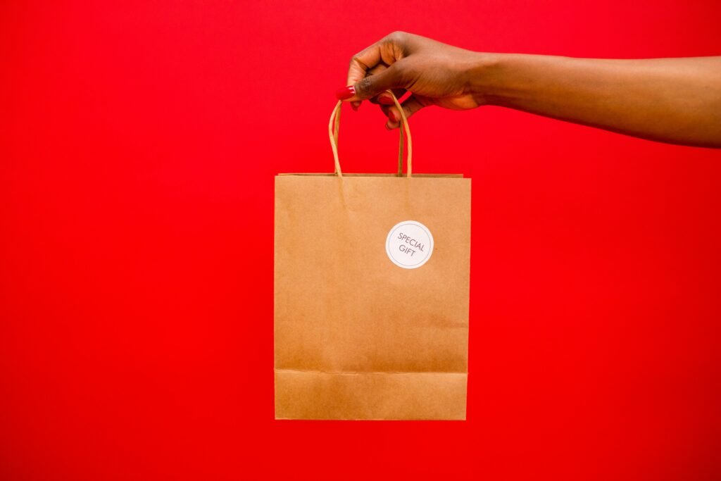 A hand holding a paper gift bag labeled 'Special Gift' against a vibrant red background.